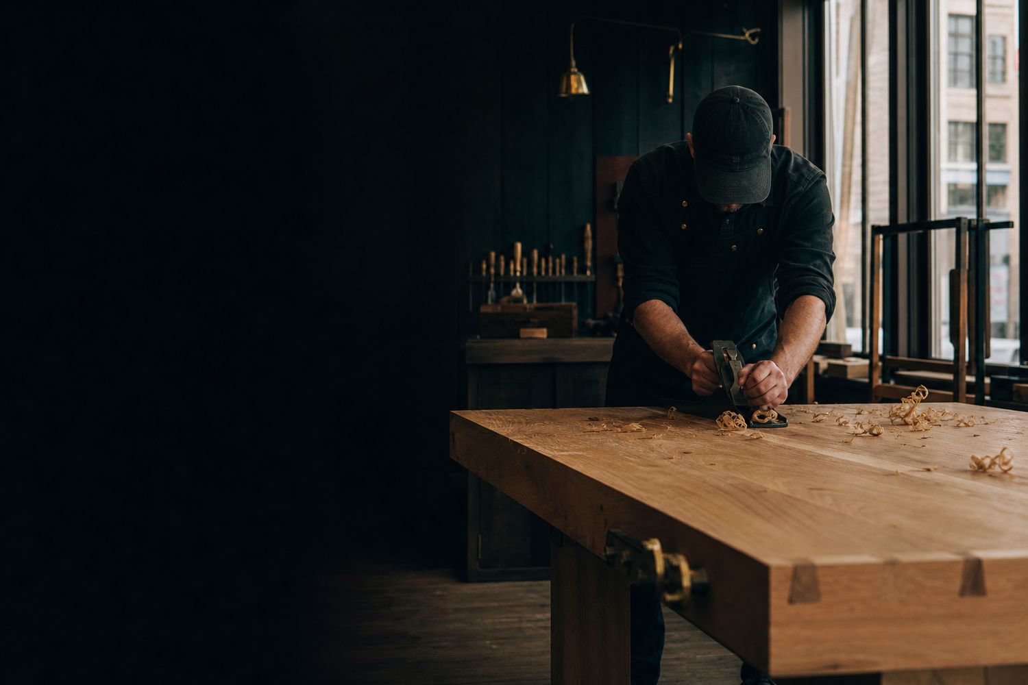 Craftsperson hand-planing oak at a workshop bench